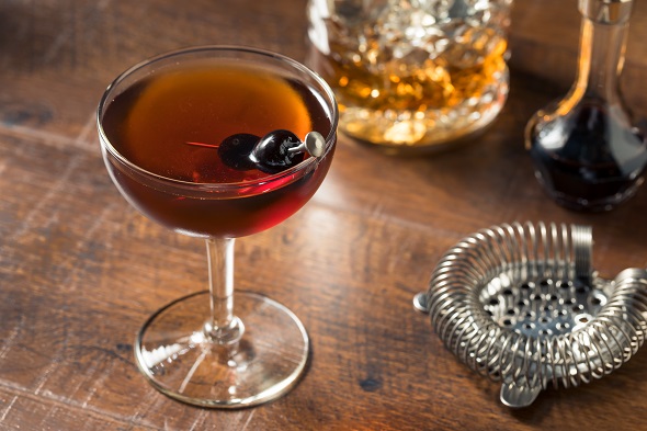Koktejl Manhattan namíchaný podle receptu a ozdobený koktejlovou třešní